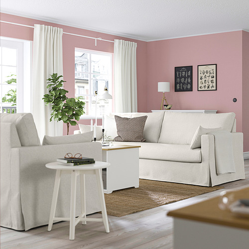 Acogedora sala de estar con sofá HYLTARP beige, almohada estampada, paredes rosas y decoración moderna.