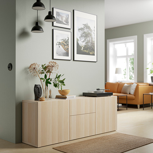 Sala de estar moderna con estante BESTÅ blanco, flores secas, plato giratorio, sofá naranja, tres lámparas colgantes.
