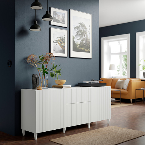 Moderno salón con aparador BESTÅ, sofá naranja y lámparas colgantes.