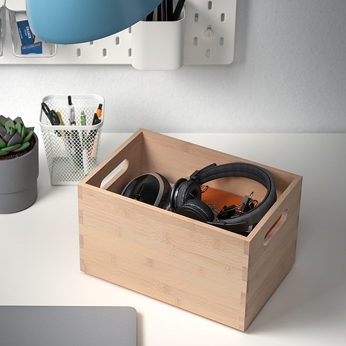 Caja de madera que sostiene auriculares sobre el escritorio, rodeada de accesorios de escritorio.