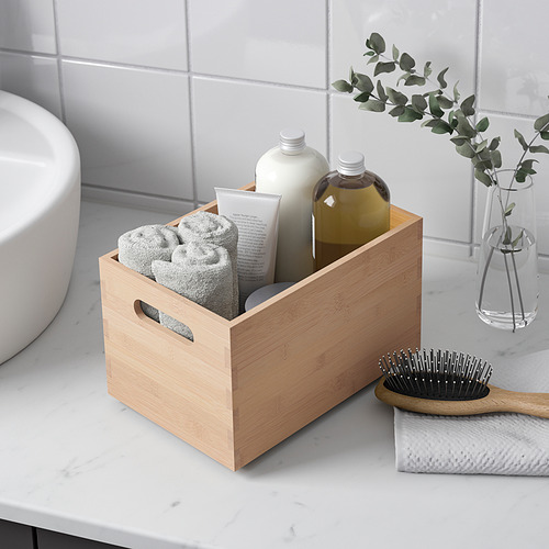 Organizador de baño de madera con toallas y artículos de tocador, junto a un cepillo para el cabello.