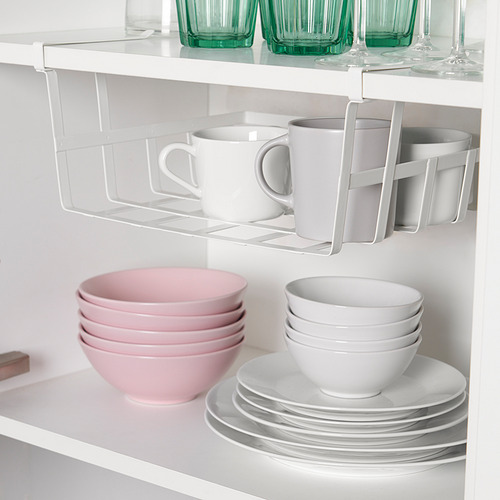 Un armario de cocina con estantes que muestran una cesta de almacenamiento con clip que contiene tazas, encima de cuencos y platos apilados de color rosa y blanco.