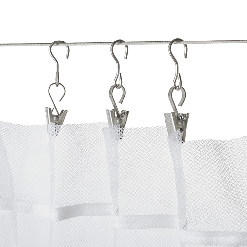 Tres cortinas blancas colgaban uniformemente con clips y ganchos en forma de S en una varilla de metal.