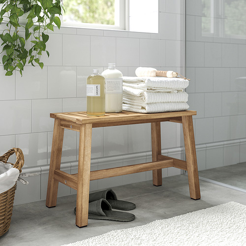 Banco de baño de madera con toallas y botellas.