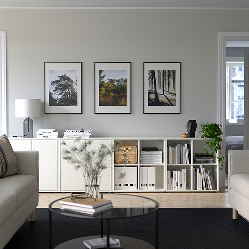 Minimalist living room with EKET storage, books, decor, nature photos, round coffee table, gray sofa, and natural light.