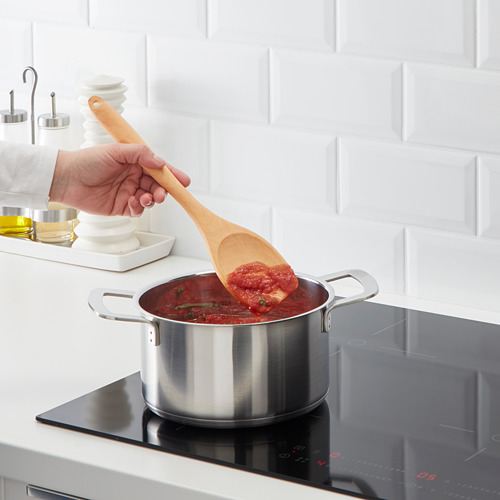 Cocine la salsa roja revolviendo en una estufa moderna.