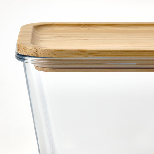Primer plano de un recipiente de vidrio transparente con tapa de bambú, que muestra una textura natural y un diseño de sellado hermético.