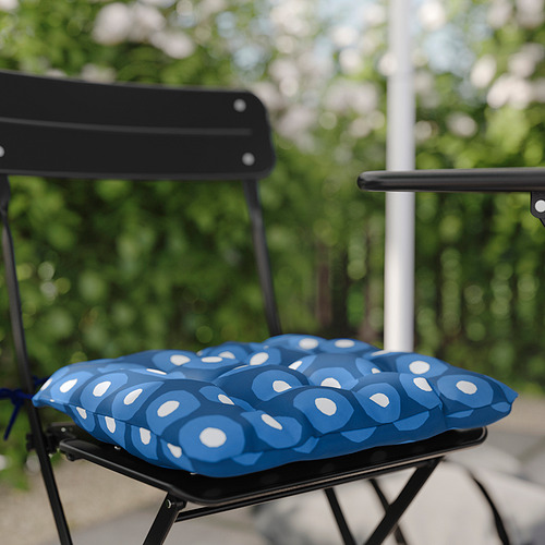 Silla de metal negro con cojín azul de estampado circular en el exterior.