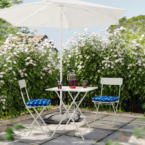 Balcón con muebles SUNDSÖ, bebidas, flores blancas, cojines azules