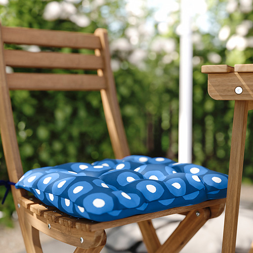 Silla de exterior azul con cojín blanco de patrón circular sobre silla de madera.