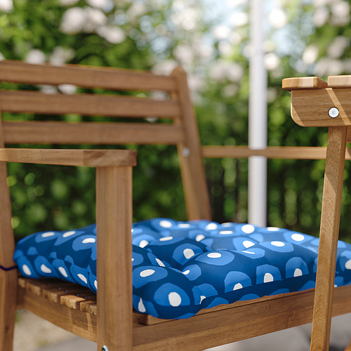 Silla de exterior de madera marrón con cojín de puntos blanco azulado.