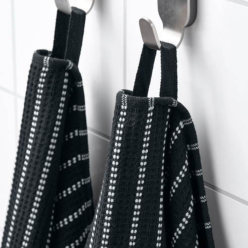 Dos toallas estampadas en blanco y negro cuelgan cuidadosamente de ganchos de metal. Las texturas de gofres y el material de algodón son evidentes.
