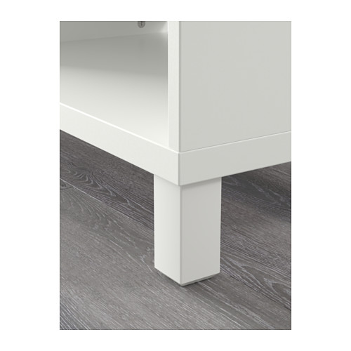 Primer plano de la pata de un mueble blanco BESTÅ sobre suelo de madera, con un diseño de alta calidad y una construcción robusta.