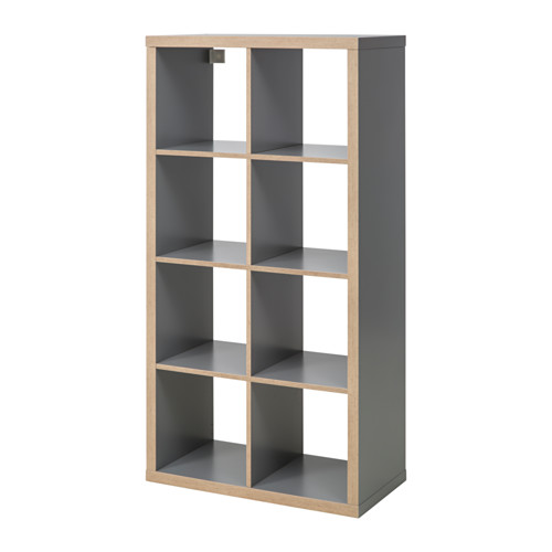 Muestra una estantería KALLAX gris vacía con múltiples compartimentos, con un diseño moderno y minimalista.