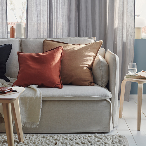 Sala de estar moderna con sofá gris, almohadas de colores, mesas auxiliares de madera y cortinas.