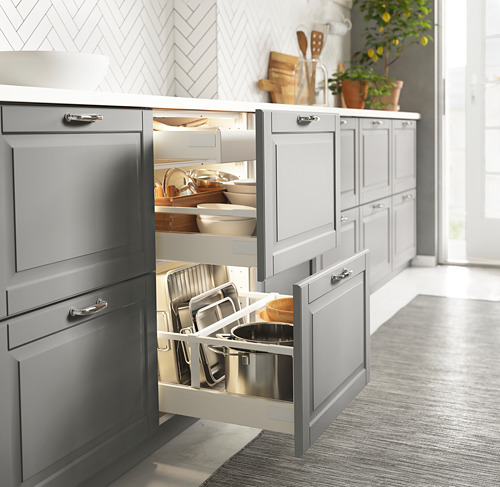 Armarios de cocina grises con cajón abierto, leds suaves encendidos, ollas, sartenes, utensilios.