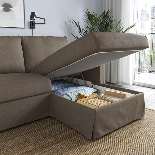 Sofá moderno con tumbona, con espacio de almacenamiento debajo del asiento lleno de mantas y juegos de mesa.