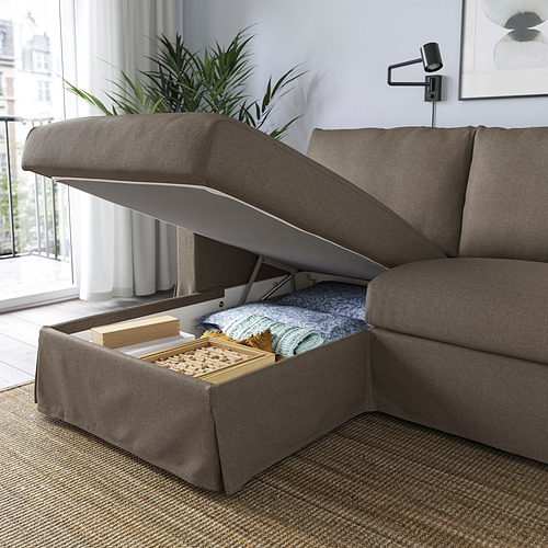 Sofá moderno con almacenaje. La tapa de la chaise longue se abre, dejando al descubierto las mantas y los juegos del interior.