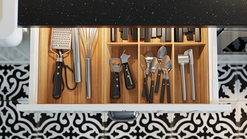 Cajón de cocina organizado con utensilios modernos negros y plateados. Compartimentos de madera, iluminación led en el interior.