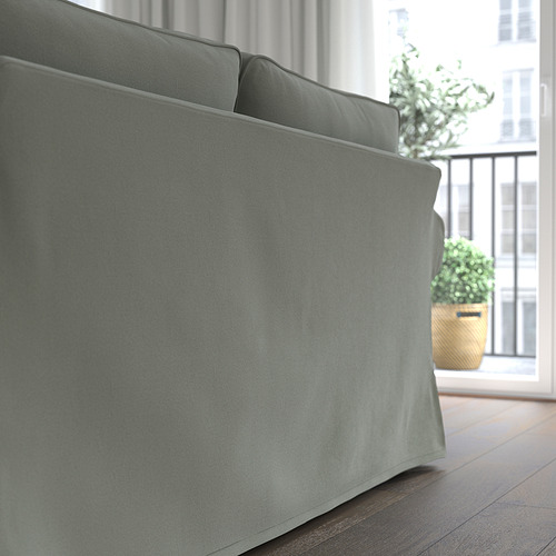Sofá moderno con cojines gruesos, funda desenfundable, cerca de ventana con plantas.