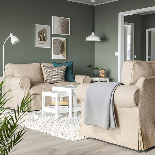 Sala de estar moderna con sofás beige EKTORP, paredes verdes, muebles blancos y arte abstracto en las paredes.