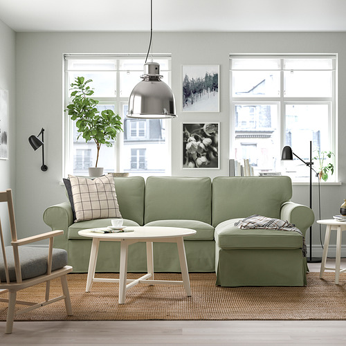 Sala de estar moderna con seccional EKTORP verde, mesa de centro blanca, grandes ventanales y lámpara colgante.