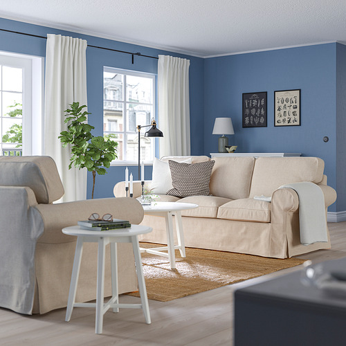 Acogedora sala de estar azul con sofá EKTORP beige, mesa auxiliar blanca y planta alta.