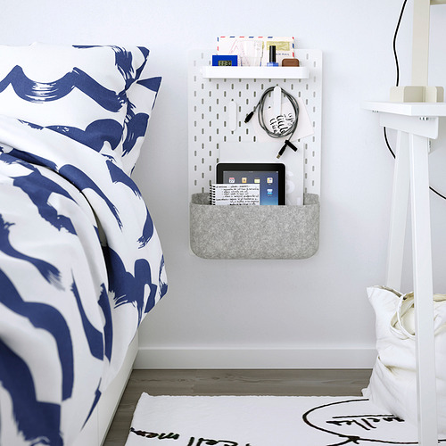 La cesta SKÅDIS en la pared sostiene la tableta, los artículos pequeños cerca de la cama estampada.