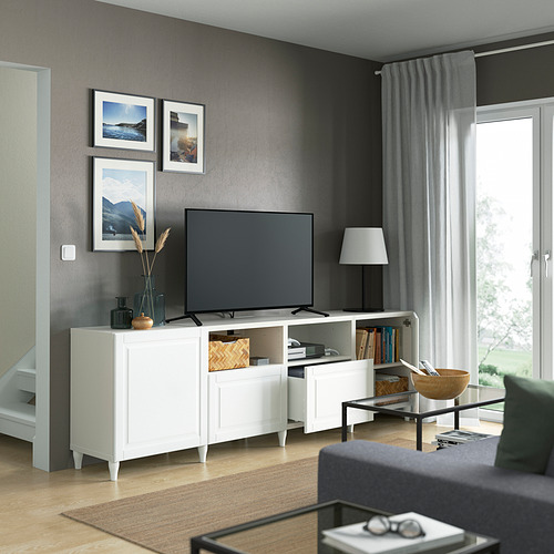 Moderno salón con mueble de tv BESTÅ, sofá gris y mesa de centro decorada con fotos y un jarrón.