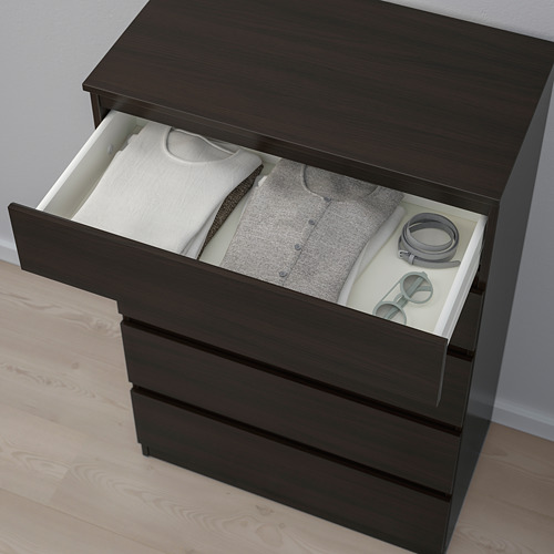 Cómoda de madera oscura con un cajón abierto que revela ropa y accesorios cuidadosamente doblados.