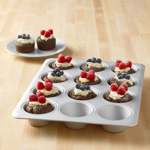 Molde para muffins relleno de bocados de brownie cubierto con fruta y glaseado.