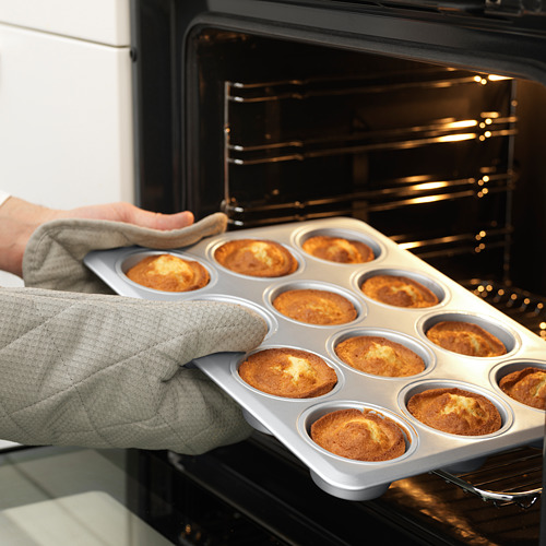 Persona que sostiene un molde para muffins con muffins horneados, usándolo para hornear, mostrando durabilidad y versatilidad.
