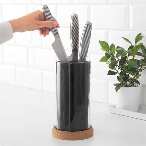 Persona agarrando cuchillo del bloque flexible IKEA 365+ en el mostrador; planta al lado.