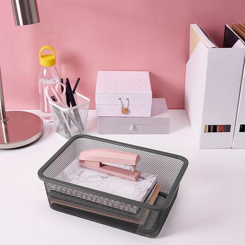 Configuración de escritorio organizada con caja de almacenamiento de malla metálica, tijeras rosas y una caja blanca para artículos de papelería.