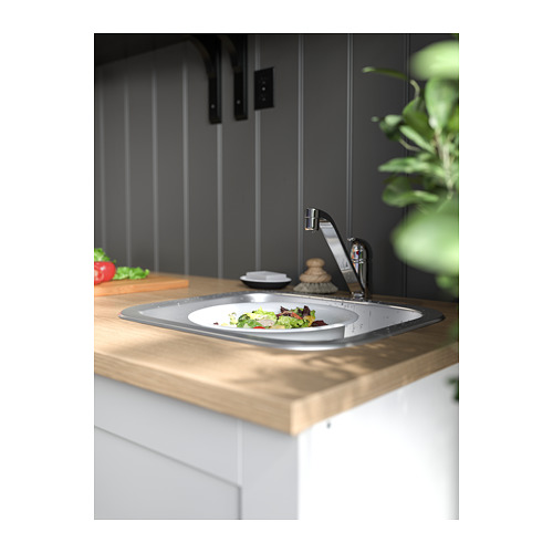 Moderno fregadero de cocina en acero inoxidable, instalado en encimera de madera, con un plato de ensalada.