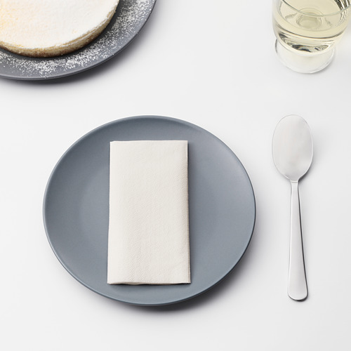 Una mesa con un plato azul con una servilleta blanca cuidadosamente doblada, una cuchara de metal y un vaso de agua. Perfecto para servir cenas o postres.
