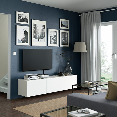 Sala de estar moderna con paredes azul oscuro, banco de televisión blanco, televisor de pantalla plana, cinco fotos en blanco y negro, lámpara alta, mesa de centro de vidrio, sofá gris.