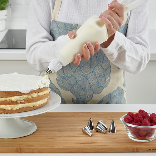 Baker decora el pastel con crema batida y bayas.