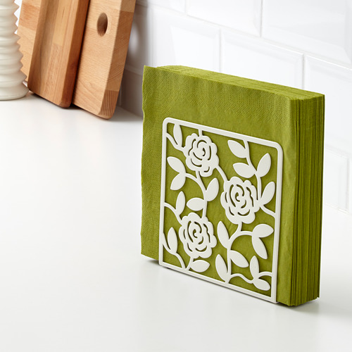 Servilletas verdes sujetas en soporte decorativo blanco con diseño de rosas. El soporte mantiene las servilletas en posición vertical y visibles.