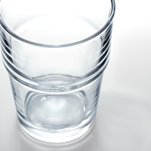 Vaso de vidrio transparente, pequeña cantidad de agua, base gruesa, apilado ordenadamente.
