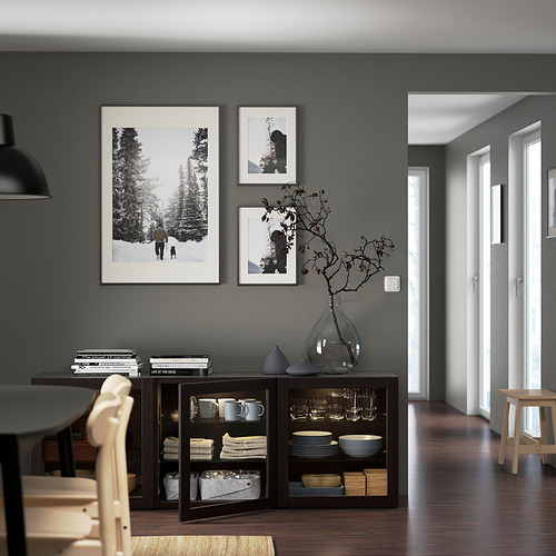 Comedor moderno con aparador BESTÅ, fotos, jarrón, libros y sillas de madera.