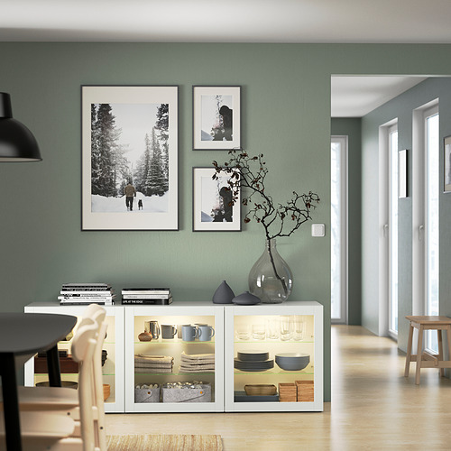 Moderna habitación verde salvia con aparador BESTÅ, impresiones artísticas y jarrón de vidrio.