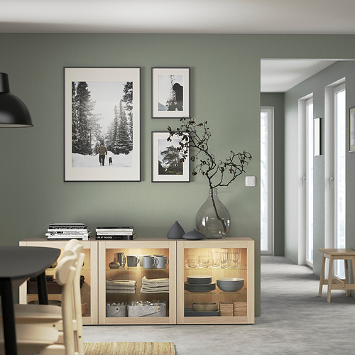 Modern dining room with BESTÅ light wood sideboard, displaying dishes and decor.