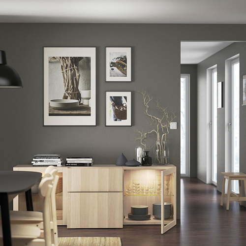 Moderno espacio de comedor con aparador ligero, cristalería, platos, ramas decorativas y arte de pared, con estantes ajustables y almacenamiento.