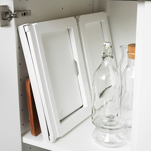 Bandeja de cama plegable almacenada verticalmente contra la pared del armario con utensilios de cocina cerca.