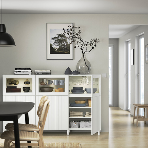 Moderno comedor con aparador, vajilla y decoración BESTÅ. Jarrón de ramas y cuadro enmarcado.