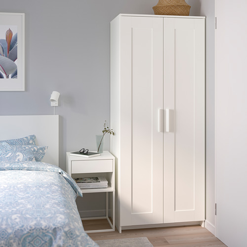 Armario alto BRIMNES blanco junto a la cama en un pequeño dormitorio.