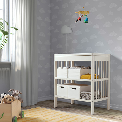 Habitación para niños con cambiador blanco GULLIVER, pared con estampado de nubes y juguetes de peluche.