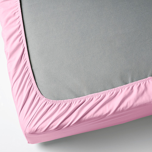Una sábana ajustable rosa cubriendo un colchón gris, mostrando bordes elásticos para un ajuste seguro.