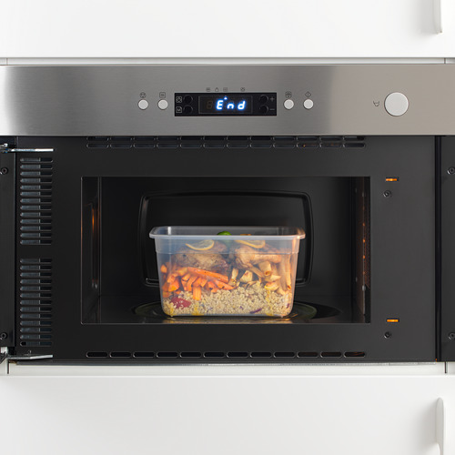 Microondas de acero inoxidable con pantalla final iluminada, calentando alimentos en un recipiente de plástico transparente.